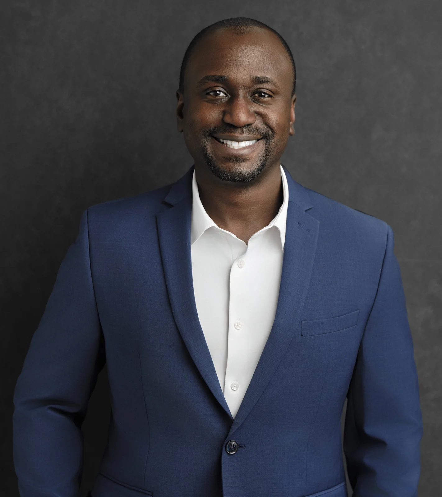 Christian Idiodi smiling in a navy jacket and white shirt